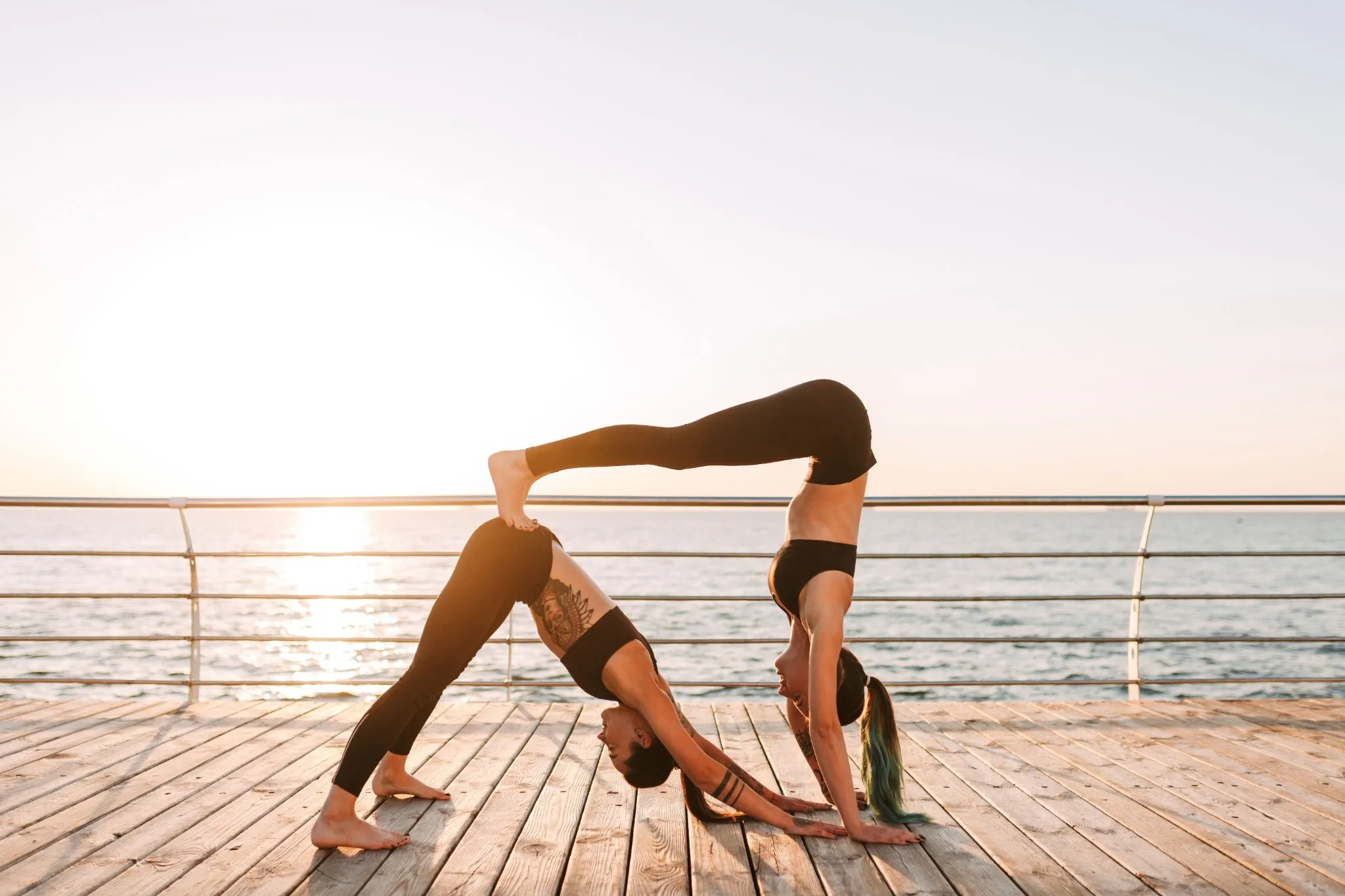2 yogis by the ocean doing the double downward facing dog, which can be a hard 2 person yoga pose.